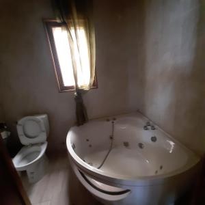 a bathroom with a tub and a toilet and a window at Ocean View Guesthouse in São Tomé