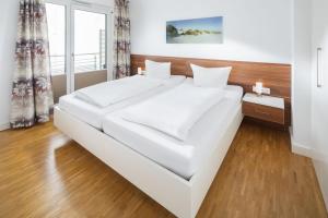 een wit bed in een kamer met een groot raam bij Schippers Huus 03 - Bremen in Norderney