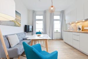 ein Wohnzimmer mit einem Sofa, einem Tisch und Stühlen in der Unterkunft Haus Menno Janssen - Ferienwohnung Bella in Norderney