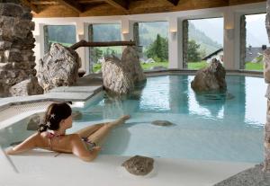 a woman laying in a hot tub in a spa at Chalet Jochpass Ferienwohnungen by HOTEL LANIG in Bad Hindelang