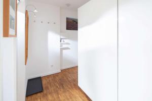 a room with white walls and wooden flooring and a hallway at Wohnung Berlin in Norderney