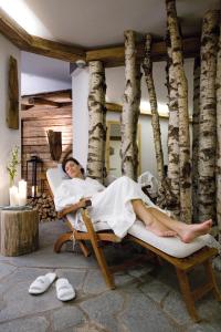 a woman laying in a bed in a room with trees at Chalet Jochpass Ferienwohnungen by HOTEL LANIG - Ferienwohnungen mit Zugang zum WellnessSpa im Hotel Lanig in Bad Hindelang