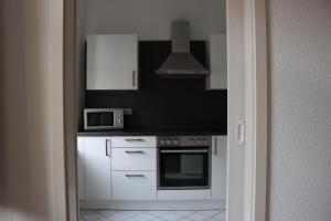 alexxanders Apartments & Studios في شيمنيتز: مطبخ مع دواليب بيضاء وميكرويف