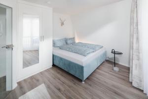 - une chambre dotée d'un lit avec des draps bleus et un miroir dans l'établissement Luisensuite, à Norderney