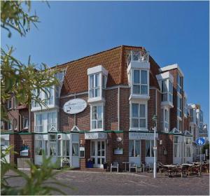 un grand bâtiment en briques avec des tables devant lui dans l'établissement Luisensuite, à Norderney