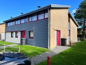 a building with a red door next to a car at Wijk de Brabander 60 in Cadzand