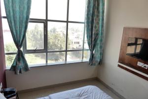 a bedroom with a bed and a large window at HOTEL IRA Mansarovar Jaipur in Jaipur