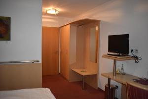 a room with a bed and a desk with a television at Hotel Alte Post Ostbevern in Ostbevern