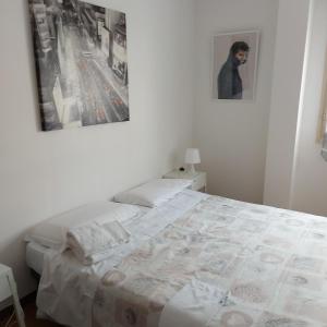 ein weißes Schlafzimmer mit einem Bett und einem Bild an der Wand in der Unterkunft Room Pappagnocca in Reggio nell'Emilia
