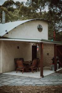 un patio con mesa y sillas frente a una casa en Three Little Pigs Escape - MAIN HOUSE ONLY en South Bruny