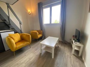 een woonkamer met een gele stoel en een tafel bij Immeuble Les Perdrix in Quimper