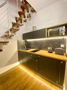 a kitchen with black cabinets and a staircase at Apartament z jacuzzi in Kraków
