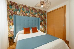 Un dormitorio con una cama azul y blanca con almohadas naranjas en Apartamentos Debambú, en Málaga