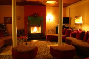 a living room with a fireplace and a couch and chairs at Parkhotel Hitzacker in Hitzacker