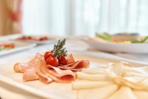 a plate of food on a table with tomatoes on it at Hotel Lovran in Lovran