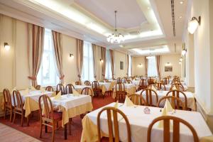 a room filled with tables and chairs with white tablecloths at Hotel Lovran in Lovran