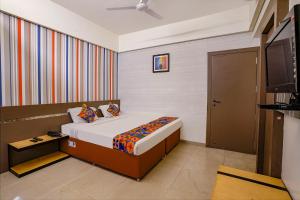 a bedroom with a bed and a flat screen tv at FabHotel Gargi Deluxe in Pune