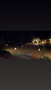 una playa por la noche con luces en el fondo en SaharaTime Camp en Hassilabied