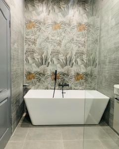 a white bath tub in a bathroom with a floral wallpaper at Blackwood Eco Lodge in Witbank