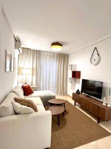sala de estar con sofá blanco y TV en Apartamentos Palangres, en Torrevieja