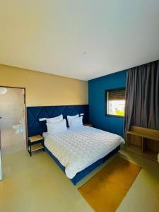 a bedroom with a large bed with a blue wall at Appart Hôtel Pyramides El Jadida in El Jadida