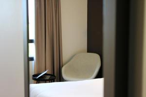 a bedroom with a chair and a bed and a window at Campanile Laval Nord in Changé