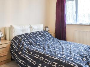 a bedroom with a bed with a blue and white blanket at Sea View in Bognor Regis