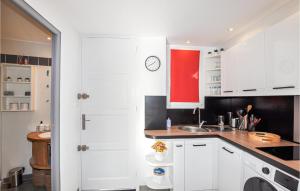 kuchnia z białymi szafkami i czerwonym oknem w obiekcie Beach Front Apartment w mieście Saint-Cyprien-Plage