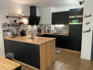 uma cozinha com armários pretos e um balcão de madeira em Le Parc em Bergerac