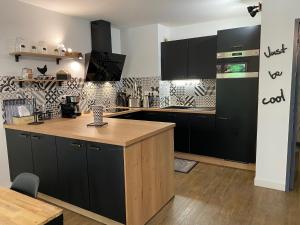 Una cocina con gabinetes negros y una encimera de madera. en Le Parc, en Bergerac