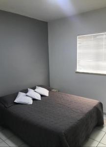 a bedroom with a bed with two pillows and a window at Apto em condomínio , portaria 24h, com área de lazer, ideal para famílias in Imperatriz