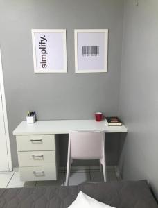 a white desk with a chair and two pictures on the wall at Impera House Ar Cond na sala e nos quartos in Imperatriz
