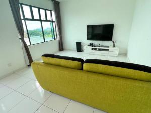 a yellow couch in a living room with a television at High class condominium 3rm Bukit Indah Johor pool gym in Johor Bahru