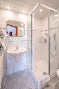 a white bathroom with a shower and a sink at Ferienwohnungen Arnspitz in Krün