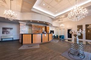 a lobby with a reception desk and chandeliers at Prestige Treasure Cove Resort, WorldHotels Elite in Prince George