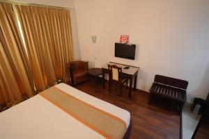 um quarto de hotel com uma cama, uma secretária e uma televisão em AQUARIA THE BOUTIQUE RESORT em Cochin