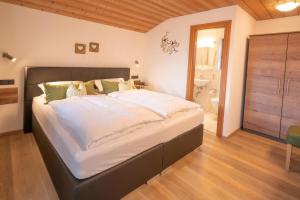 een slaapkamer met een groot bed met witte lakens bij Ferienwohnungen Arnspitz in Krün