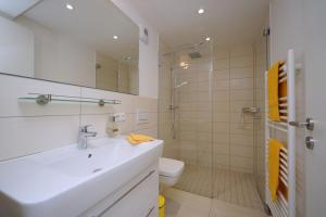 La salle de bains blanche est pourvue d'un lavabo et de toilettes. dans l'établissement APRICUM - Mein Sonnenlicht - Haus Granitz, à Binz