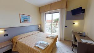 una camera con letto, scrivania e finestra di Miriam Hotel & Residence a Pietra Ligure