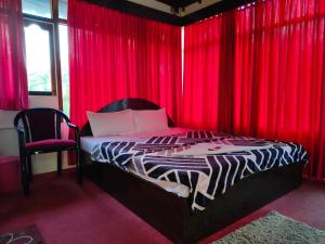 a bedroom with red curtains and a bed and a chair at Hotel Highness Sea Rock in Neil Island