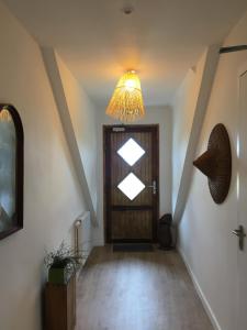 a hallway with a wooden door and a chandelier at Maison Glaz in Gâvres