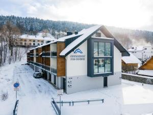 a building with a sign on it in the snow at Apartamenty Pod Stokiem 200 m do kolejki Na Skrzyczne - Dream Apart in Szczyrk