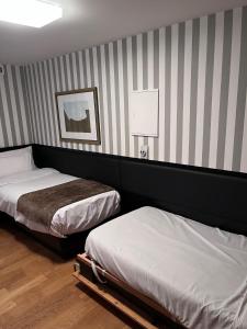 ein Schlafzimmer mit 2 Betten und einer gestreiften Wand in der Unterkunft Hôtel Ettenheim in Straßburg