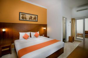 a bedroom with a large bed with orange and white sheets at Hotel Poncowinatan - Tugu in Yogyakarta