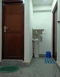 a bathroom with a toilet and a door and a sink at Nirvana Kuti in Kathmandu