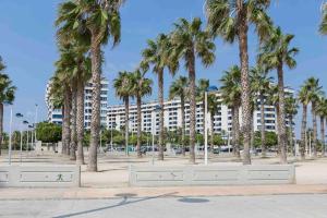 un grand bâtiment avec des palmiers devant lui dans l'établissement ApartUP Patacona Oriental, à Valence