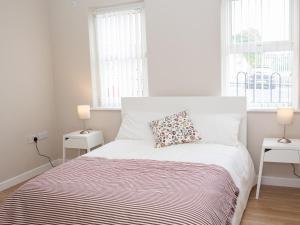 a white bedroom with a bed with a pillow on it at PG McQuaid Suite in Dungannon