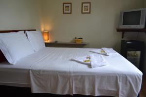 Un dormitorio con una cama blanca con toallas. en Pousada Água da Fonte, en Florianópolis