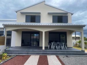 ein weißes Haus mit Glastüren und einem Tisch in der Unterkunft Villa de 3 chambres avec jardin clos et wifi a Bras Panon in Bras-Panon