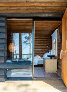 a bedroom with a large window in a log cabin at Utula Nature Retreat in Ruokolahti